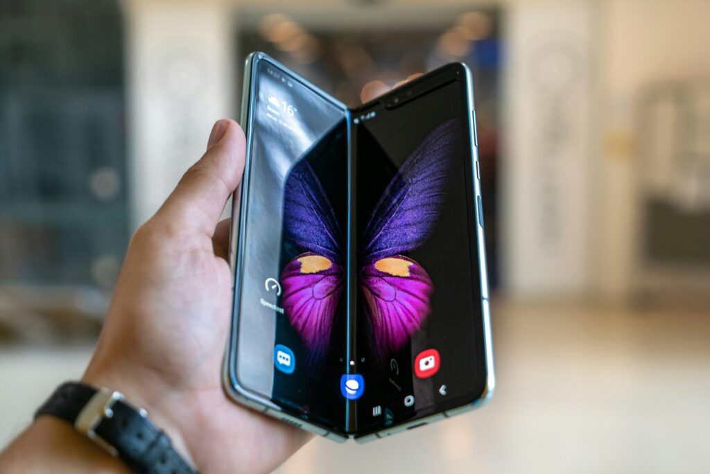Halb aufgeklapptes Samsung Galaxy Z Fold in einer Hand mit sichtbarem Innendisplay und farbigem Hintergrundbild